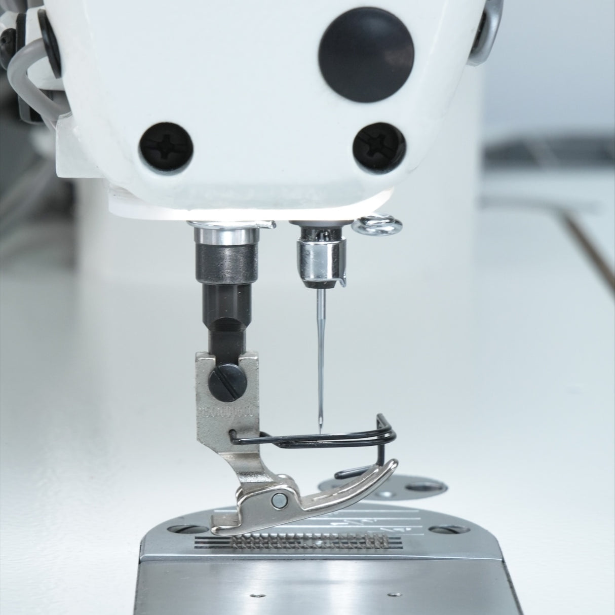 Close-up of a JACK A5E-B (A.M.H 2) sewing machine needle and presser foot on a light background
