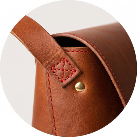 Red bartack stitch securing the strap on a cognac leather bag